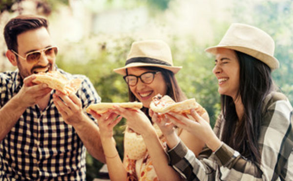 Подружки и парень едят пиццу на улице