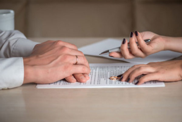 Женщина дает мужчине подписать бумаги на развод
