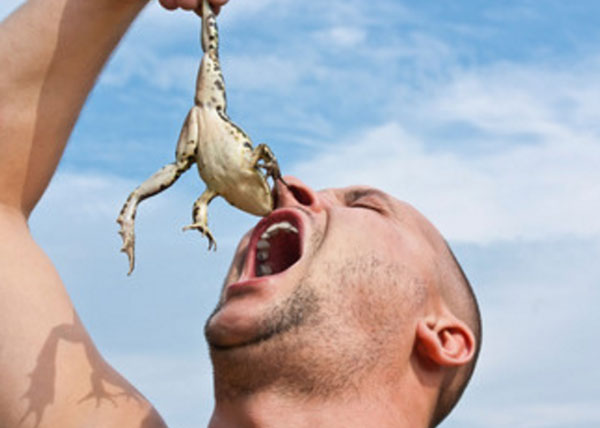 Мужчина тянет в рот живую лягушку
