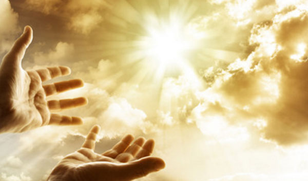 Руки человека тянутся к небу, на котором раздвинулись тучи и вышло солнце