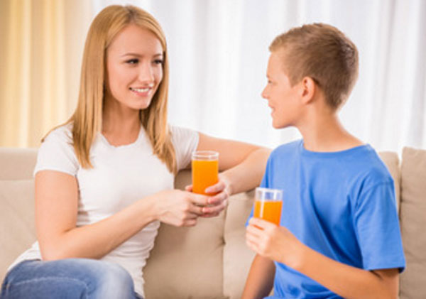 Мама общается с сыном. У обоих в руках стакан апельсинового сока
