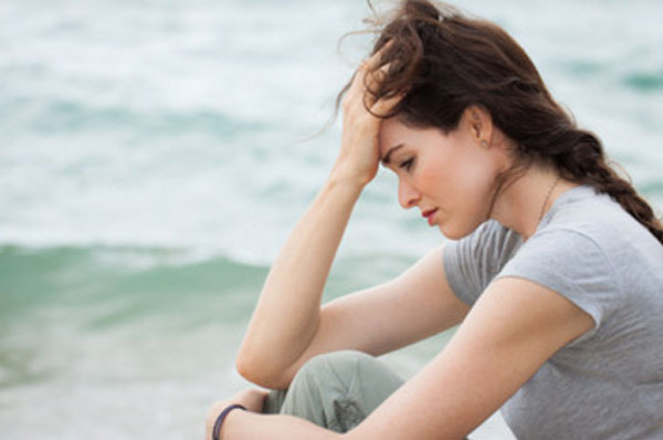 Расстроенная одинокая женщина сидит на берегу