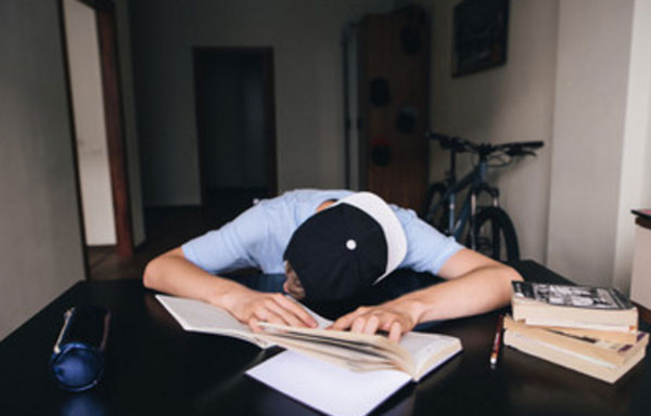Парень уснул на столе с учебниками