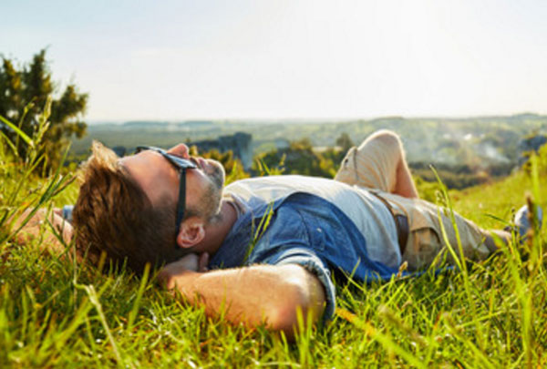 Спокойный и счастливый мужчина лежит на траве