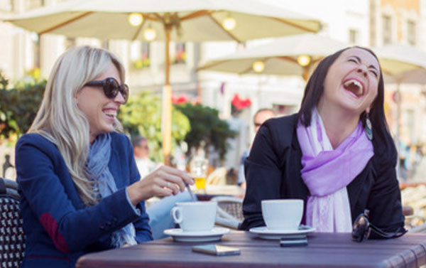 Женщины сидят в кафе и смеются
