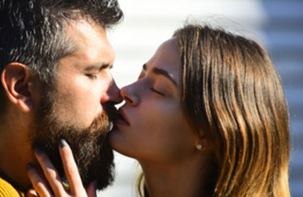 Девушка нежно целует бородатого мужчину