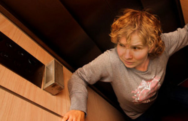 Женщина в ужасе, сидит на полу лифта