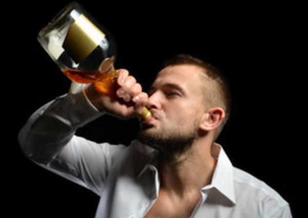 Мужчина с горла пьет спиртной напиток