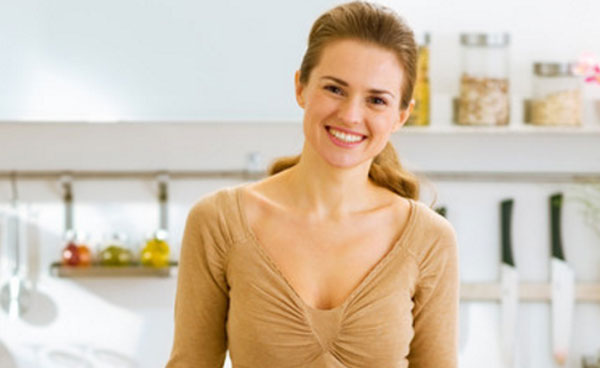 Женщина улыбается. Она стоит на своей кухне