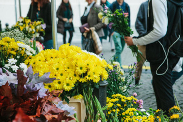 Парень стоит со скромным букетом в руке возле цветочного магазина