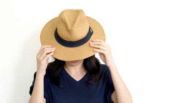 Девушка прячет лицо под шляпой