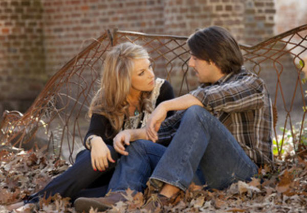 Парень с девушкой сидят в опавших листьях и серьезно разговаривают