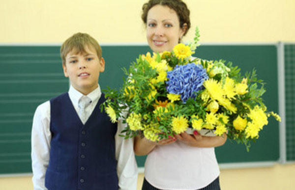 Учительница держит букет цветов. рядом стоит мальчик-подросток