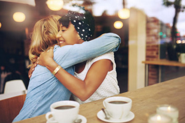 Женщины в кафе, сочувственно обнимают друг друга