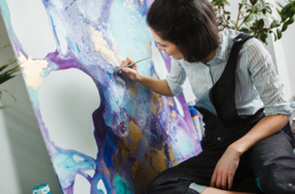 Женщина рисует на холсте