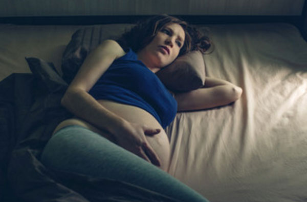 Беременная женщина лежит в темноте и не может уснуть