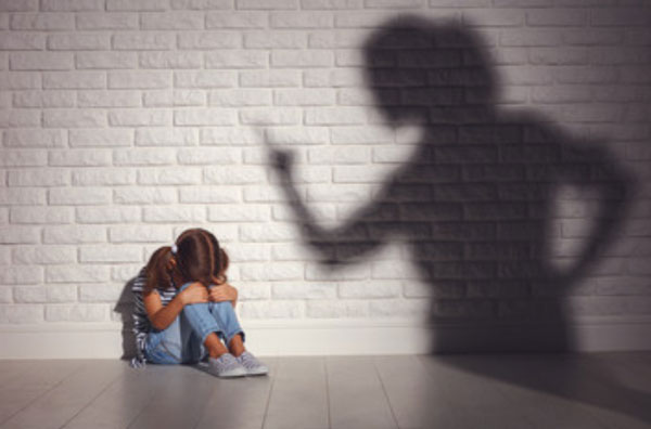 Девочка сидит возле стены, спрятала свое лицо. На стене тень матери, которая за что-то ругает