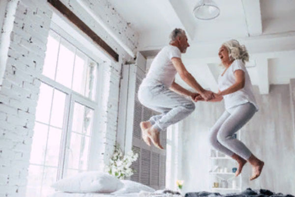 Мужчина и женщина пенсионного возраста прыгают на постели, как молодые