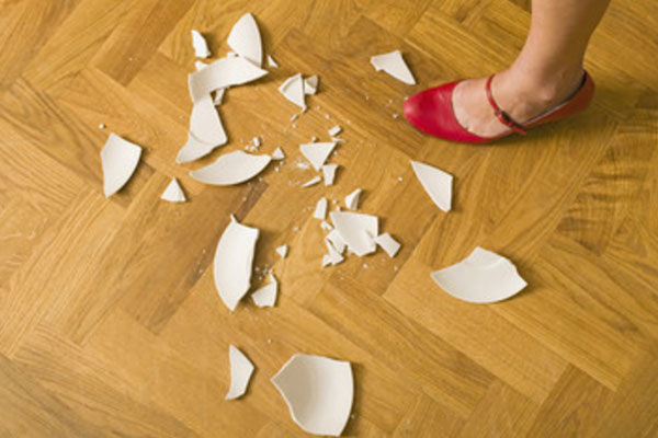 Разбитая тарелка на полу и ножка девушки