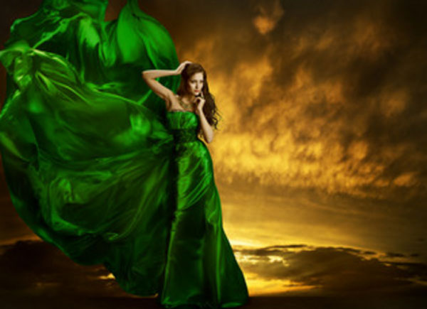 Женщина в зеленом вечернем платье, которое раздувается ветром