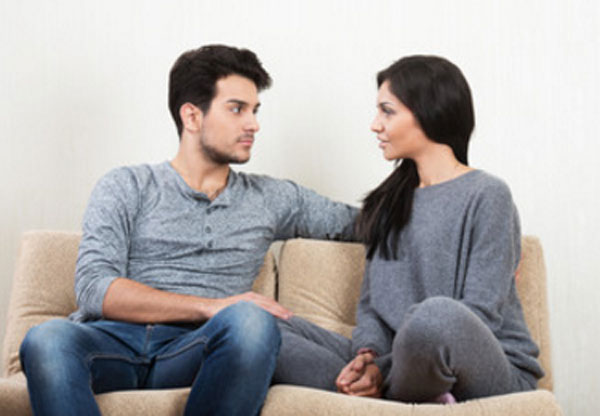 Женщина с парнем сидят на диване и смотрят друг на друга