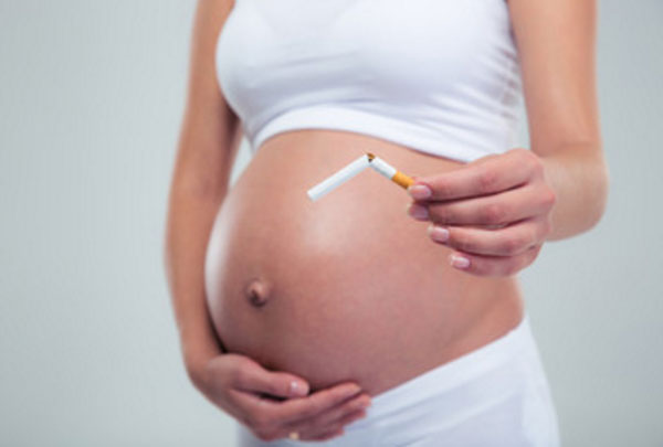 Беременная женщина с поломанной сигаретой в руке