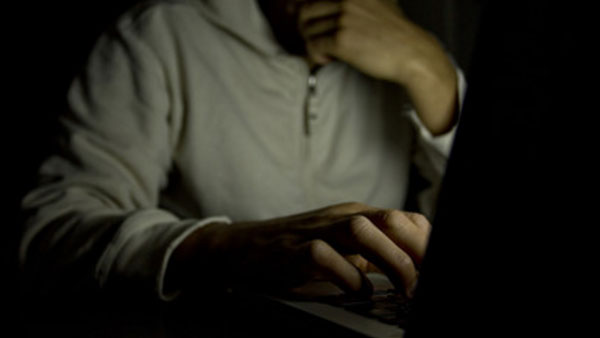 Мужчина в темноте сидит перед ноутбуком