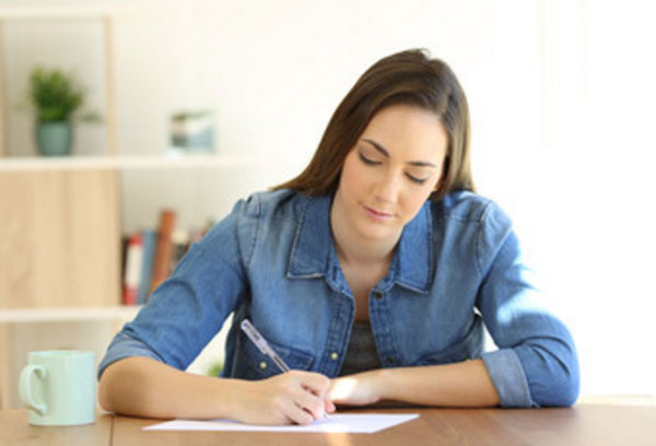 Женщина что-то пишет на листке бумаги