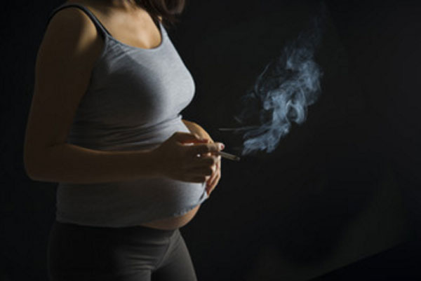 Беременная женщина с сигаретой в руке