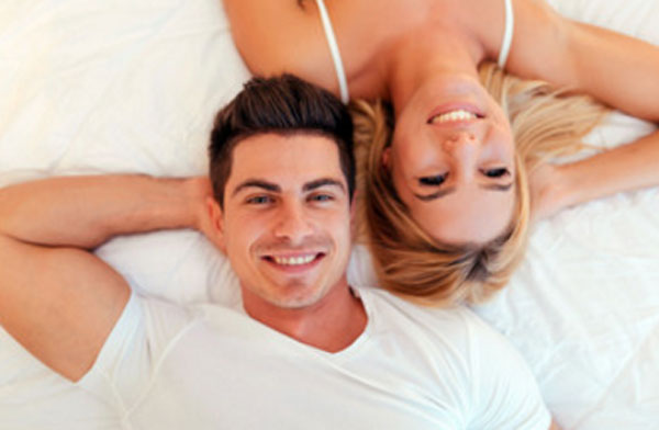 Муж и жена лежат на кровати &quot,валетом&quot,, улыбаются
