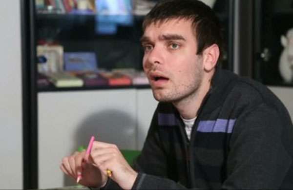Аутист с карандашом в руках. У него открыт рот