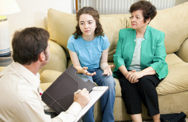 Девочка с бабушкой сидят на диване. с ними общается психотерапевт