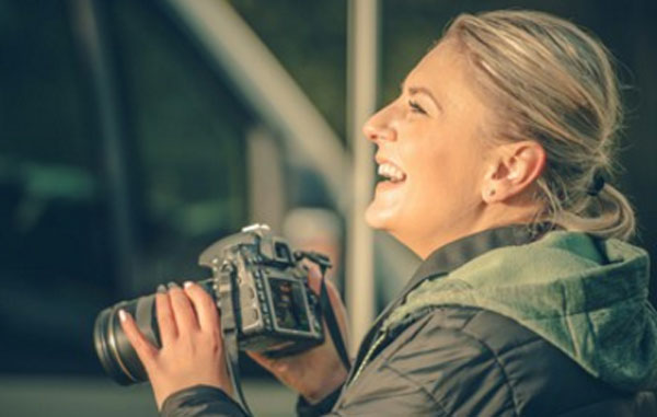 Женщина с фотоаппаратом в руках. Она смеется