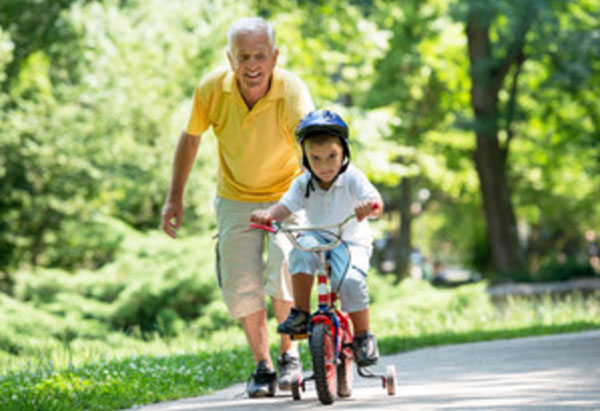 Дедушка идет за внуком, который едит на велосипеде
