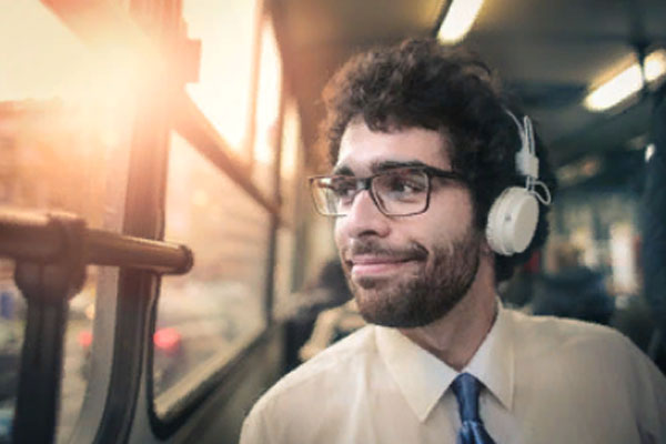 Счастливый мужчина едет в транспорте, слушает музыку в наушниках