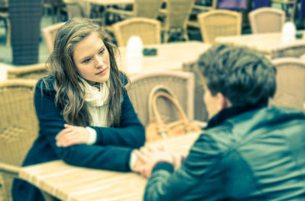 Парень с девушкой сидят за столиком в кафе. молодой человек просит прощения