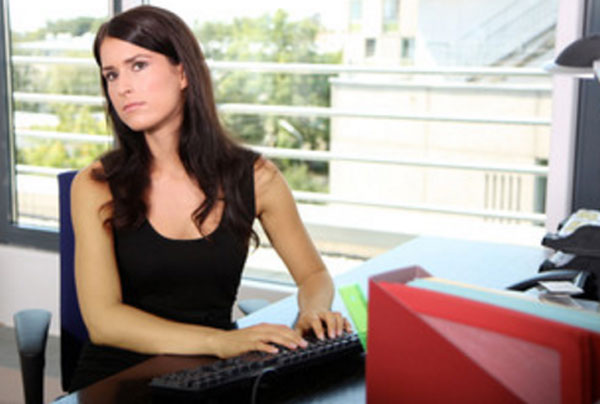 Женщина работает за компьютером, смотрит, что происходит с боку от нее