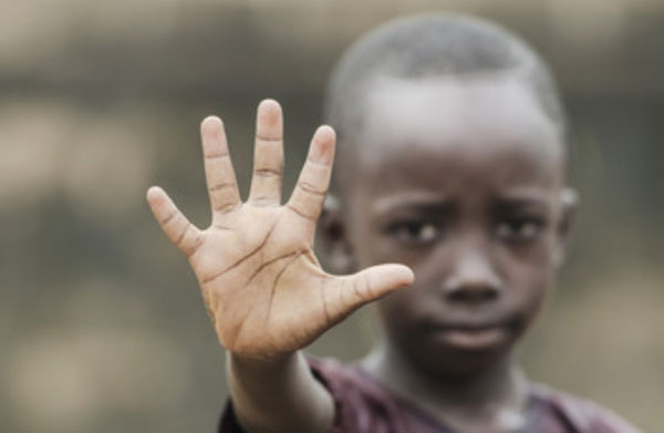 Мальчик афроамериканец с грустным лицом выставил перед собой руку, демонстрируя светлую ладонь 