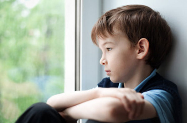 Печальный ребенок сидит на окне