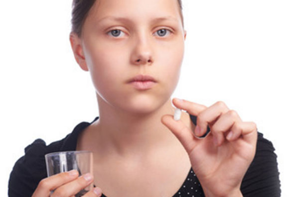 Девочка - подросток с таблеткой и стаканом воды в руках