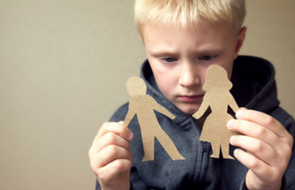Мальчик держит в руках картонную фигурку мужчины и женщины. Он расстроен