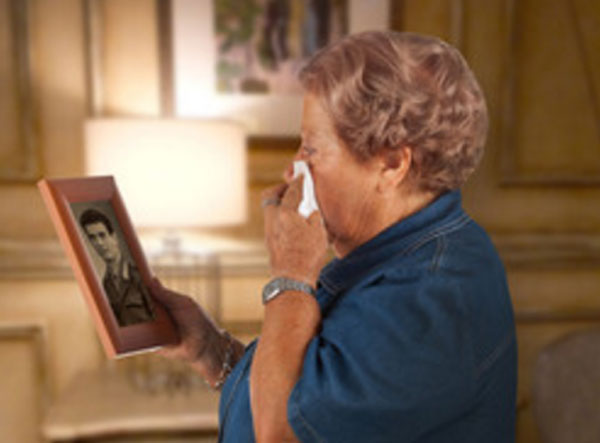 Пожилая женщина плачет, глядя на старое фото