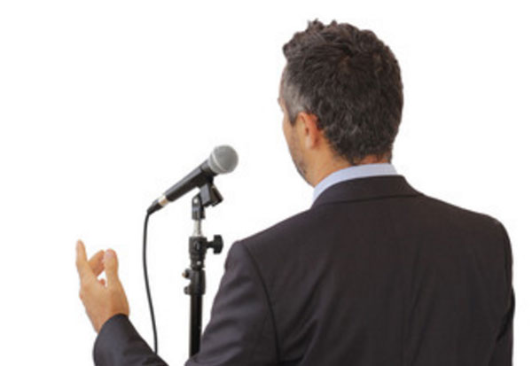 Вид ухоженного мужчины в костюме, который уверенно говорит перед микрофоном